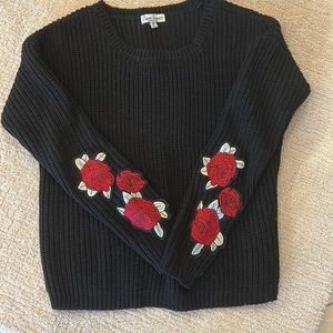 Black sweater with appliquéd roses on sleeves